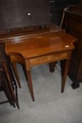 An Edwardian mahogany and inlaid fold over card table of shaped form on square tapered legs, width