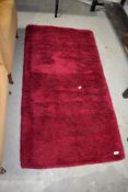 A vintage fireside rug, in deep maroon pile, approx. 135 x 70cm