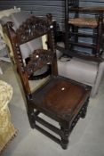 A period oak solid seat hall chair having carved back