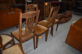 A set of four early 20th century golden oak dining chairs having rail backs, later dralon