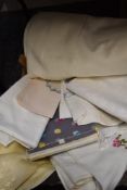 A box full of vintage and retro table linen including damask and some embroidered items.