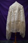A large vintage cream shawl Having extensive embroidery and fringed edges.