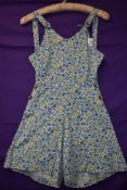 A 1940s cotton playsuit having bright floral print, buttons to both sides and buttons to front of