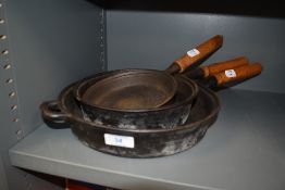 A selection of wooden handled cast iron skillet frying or sauce pans