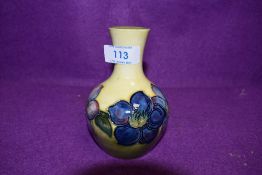 A Moorcroft vase having pale yellow ground and blue hued floral design.