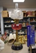 A large standing Victorian oild lamp having twisted brass stem cranberry glass well and etched shade