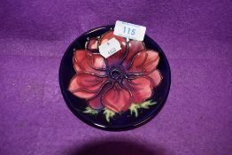 A Moorcroft pin dish having dark blue ground and Anemone to centre.