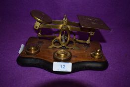 A set of brass apothecary scales on wooden mount with some weights.