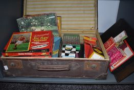 A vintage travel case containing a collection of vintage games and jigsaws including Monopoly,