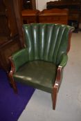 A vintage green leather or rexine fan back armchair on wooden frame