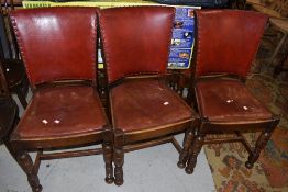 A set of six early 20th Century oak frame dining chairs having red leather seats and backs