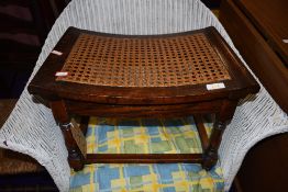 An oak framed cane seated shaped stool