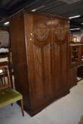 A mid 20th Century oak wardrobe and dressing table having shield and linen fold decoration, robe