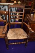 A traditional stained frame Lancashire or similar spindle back carver chair having rush seating
