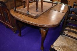 A light stained mahogany winding dining table with leaf