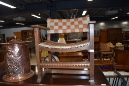 An Arts and Crafts style low carver chair, having contrasting leather strap top and shaped seat,