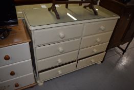 A cream bedroom chest of four by four drawers, width approx. 110cm