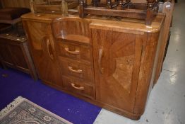 A 1930s oak and ply sideboard of interesting design having central recess over three drawers flanked