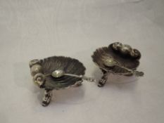 A pair of Victorian silver salts in the form of scallop shells on trefoil mythical fish feet,