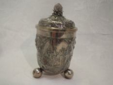 A Swiss silver lidded canister having trefoil bun feet, gilt interior and repousse floral decoration