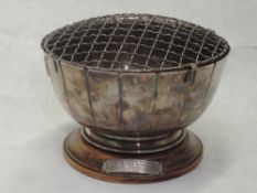 A silver rose bowl having fluted decoration, wire flower grill and a wooden presentation plinth,