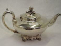 A Georgian silver teapot of plain compressed circular form having bracket feet, scroll handle and
