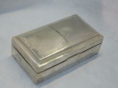 A silver cigarette box of rectangular form having engine turned wave decoration to lid with crest to
