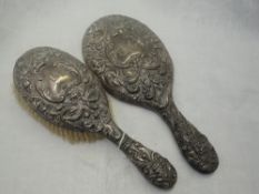 A Victorian silver brush and hand mirror having heavily embossed mask, bird and scroll decoration,