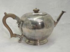 A silver teapot of plain circular form having fruit wood handle and knop, engraved decoration to lid