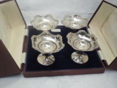 A cased set of four small silver tazzas having pierced and moulded decoration to bowls on weighted