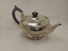 A silver breakfast teapot of plain squat circular form having hard wood handle, pedestal foot and