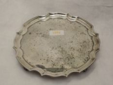 A silver card tray of plain form having monogram to centre, pie crust rim and quadrafoil scroll