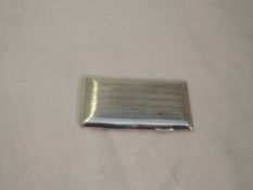 A silver card case of rectangular form having spring hinge, engine turned stripe decoration and gilt