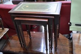 A reproduction mahogany effect nest of three tables having skiver tops
