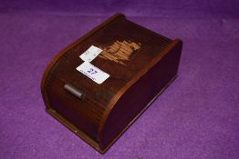 A vintage wooden roll top cigarette box with kinetic internal movement, having ship design to top.