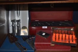 An assortment of flat ware including boxed spoons and wine tools in display case.