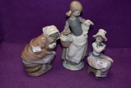 A Lladro figurine, Girl with Lamb 4835 and two Nao figurines, Girl with Duck in Basket and Girl with