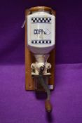 A vintage wall mounted ceramic crank handed coffee grinder with removable glass container to collect