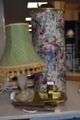 A brass candle stick holder, a table lamp with shade,an umbrella/stick or similar lidded storage