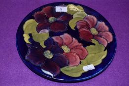 A Vintage Moorcroft plate having dark blue ground and anemone or clematis pattern.