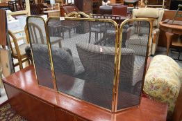 A traditional brass folding fire guard