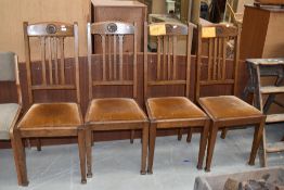A set of four early 20th century golden oak dining chairs having rail backs, later dralon