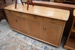 A light stained side board in an Ercol style having bifold doors, dimensions approx. W160cm H75cm