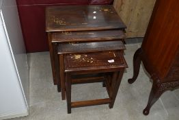 An Oriental style hardwood nest of three table with brass inlay