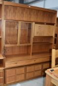 A vintage teak Nathan wall unit, having glazed display and lockable cocktail section, over triple