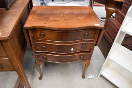 A reproduction yew wood serpentine bedside or similar chest of drawers, with winged top