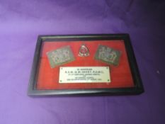 A framed WW2 Memorial consisting of two shoulder badges, cap badge and plaque reading In Memoriam