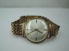 A gents 9ct gold wrist watch by Mondia having a baton numeral dial to silvered face in a 9ct gold