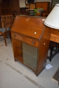 An oak bureau having glass book shelf under