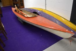 A vintage two person canoe and selection of oars and paddle